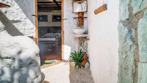Un intérieur rustique avec un mur en pierre, une porte en bois et un petit lavabo.