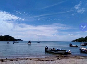 A coastal scene with several boats on calm waters, a clear sky, and distant landforms. - Caribbean house,  near the sea (Santa Marta)