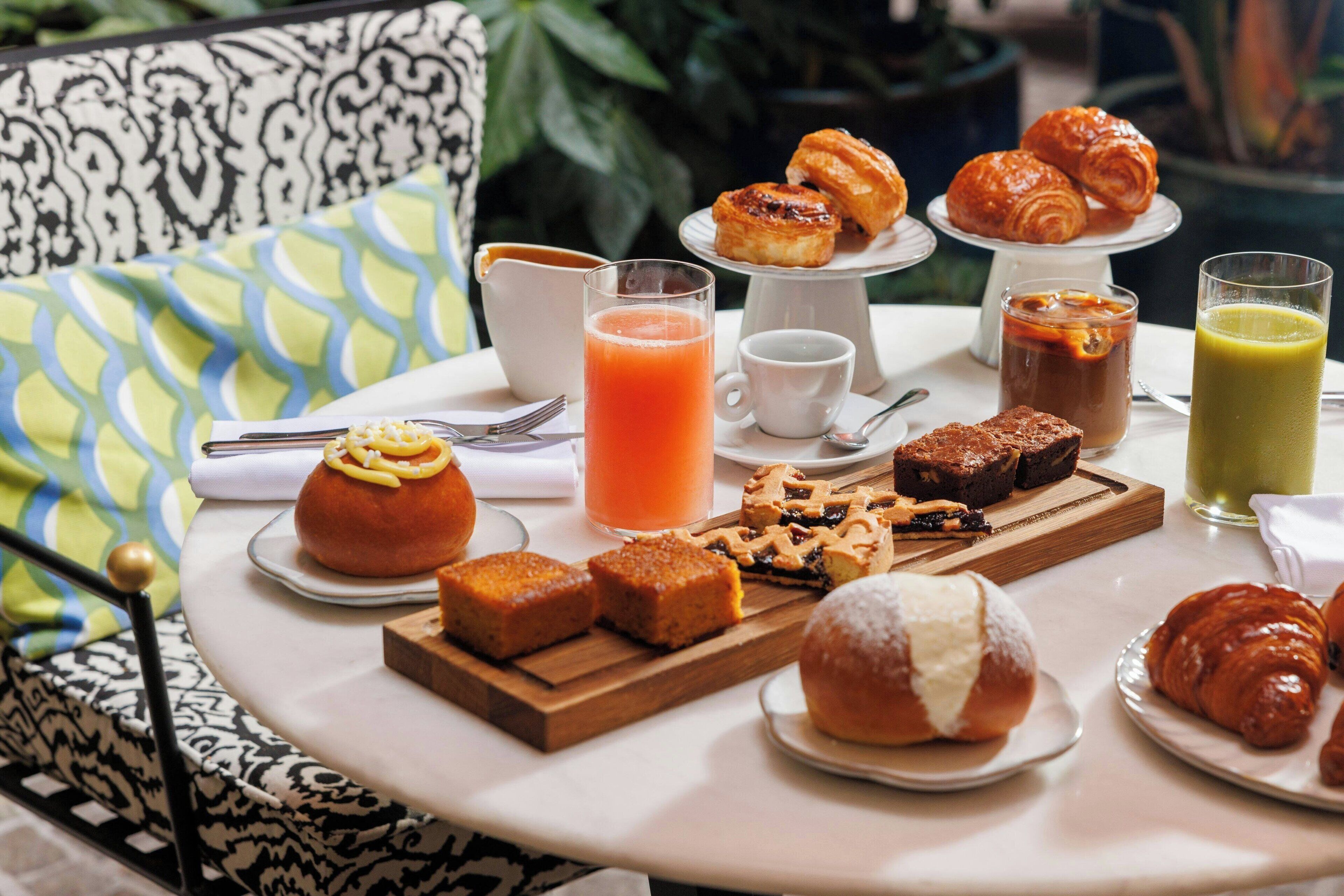 A breakfast table with pastries, a coffee pot, and a juice pitcher.