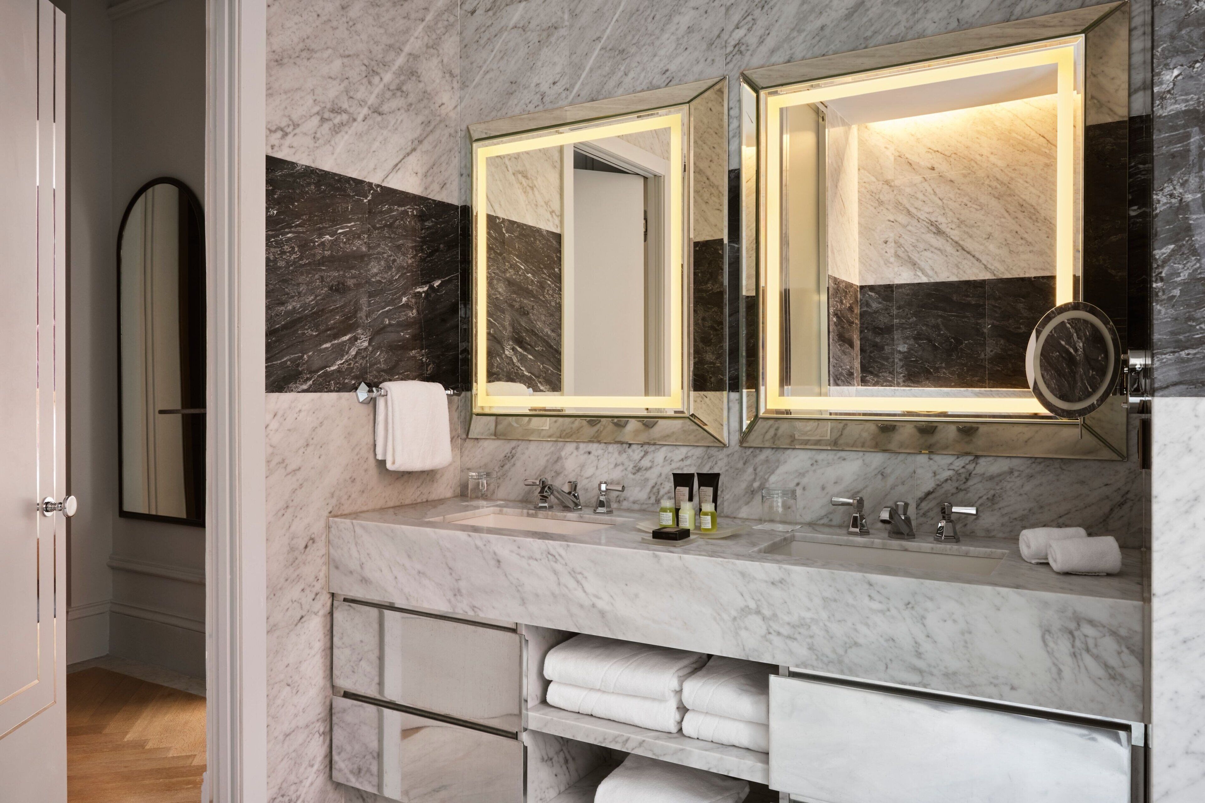 A modern bathroom with marble countertops, dual mirrors, and a built-in towel rack.