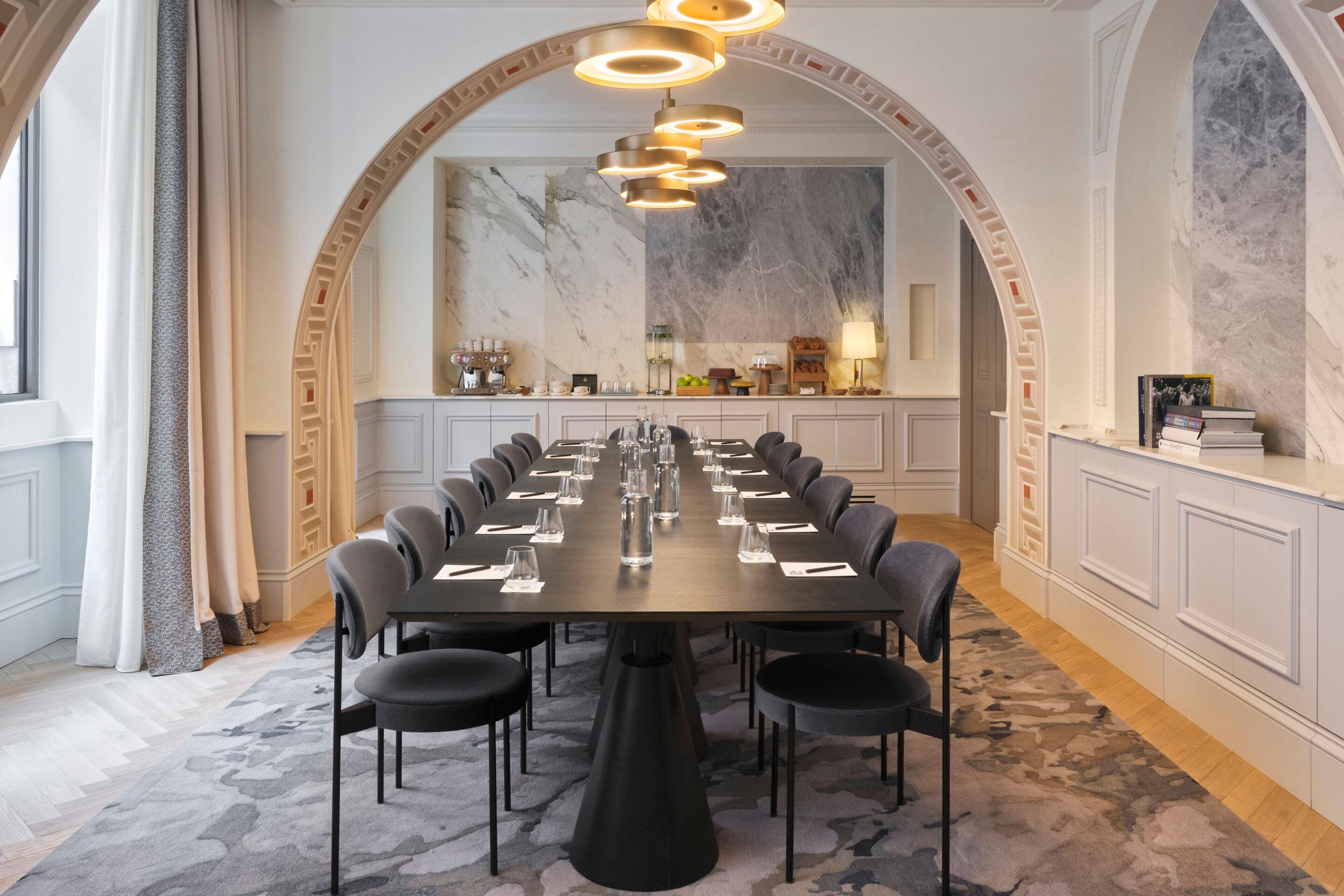 A conference room with a long table, multiple chairs, and a modern chandelier.