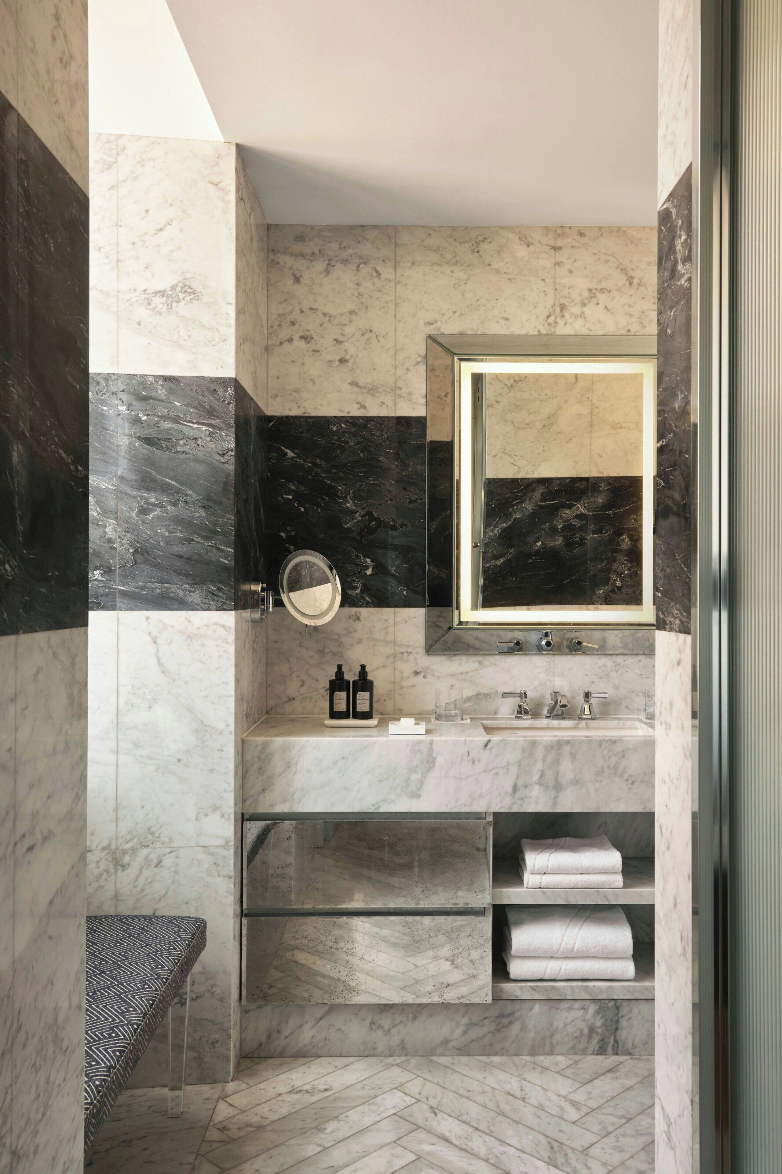 Un baño moderno con tocador de mármol, un espejo grande y estantes empotrados para toallas.