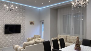 A modern dining area with a chandelier, a flat-screen TV, patterned wallpaper, and a Christmas tree. - Luxury in downtown Debrecen (Debrecen)