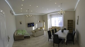 A spacious living room with a dining area, a sofa set, and a chandelier. - Luxury in downtown Debrecen (Debrecen)
