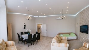 A modern living room with a dining area, a sofa, and a TV mounted on the wall. - Luxury in downtown Debrecen (Debrecen)
