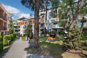 Un edificio residencial con varios balcones, un parque infantil y un sendero pavimentado.