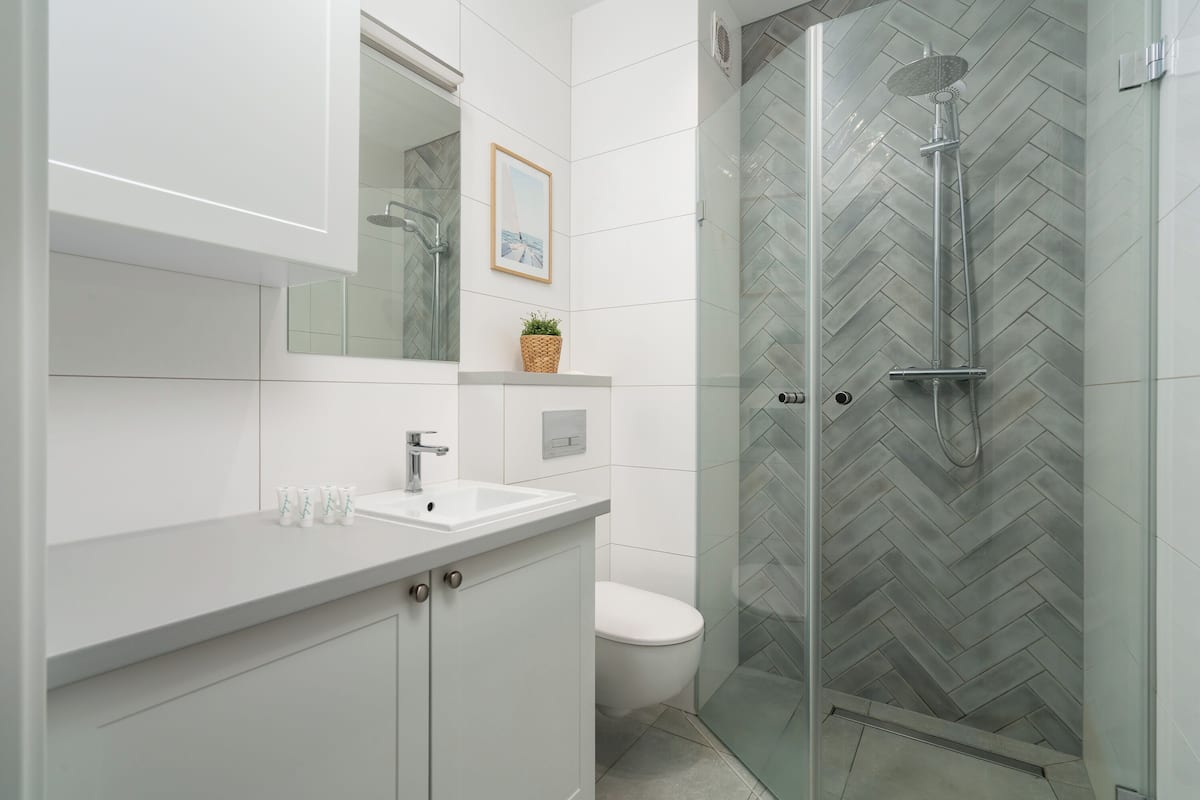 A modern bathroom with a glass-enclosed shower, a white sink, and a toilet.