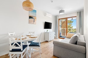 A modern living room with a dining area, a flat-screen TV, and a large window with a view. - HoliApart w Nautikka Park (Krynica Morska)