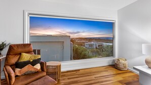 A room with a large window offering a view of a cityscape at sunset. - Luxurious Terrace Hideaway with Heated Pool (Ocean Grove)