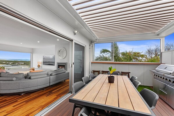 A modern living room with a sofa, a dining table, and a grill.