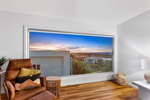 A room with a large window offering a view of a cityscape at sunset.