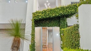 A modern building with a minimalist design, featuring a stone pathway leading to a glass door entrance. - Luxurious Terrace Hideaway with Heated Pool (Ocean Grove)