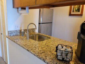 A kitchen with granite countertops, stainless steel appliances, and a dish rack.