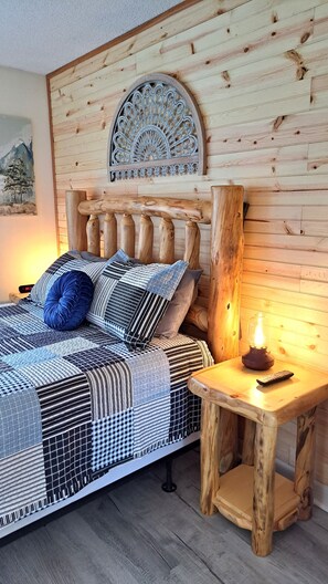 A bed with a patterned bedspread, pillows, and a headboard with a decorative metal piece. - Mountain Villa Magnificent Views - 2 Pools, Hot Tub & Fireplace (Gatlinburg)