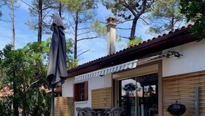 A house with a patio, outdoor seating, and a barbecue grill.