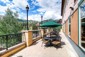 Enjoy a serene mountain view from this outdoor patio, surrounded by comfortable seating and a stylish railing.