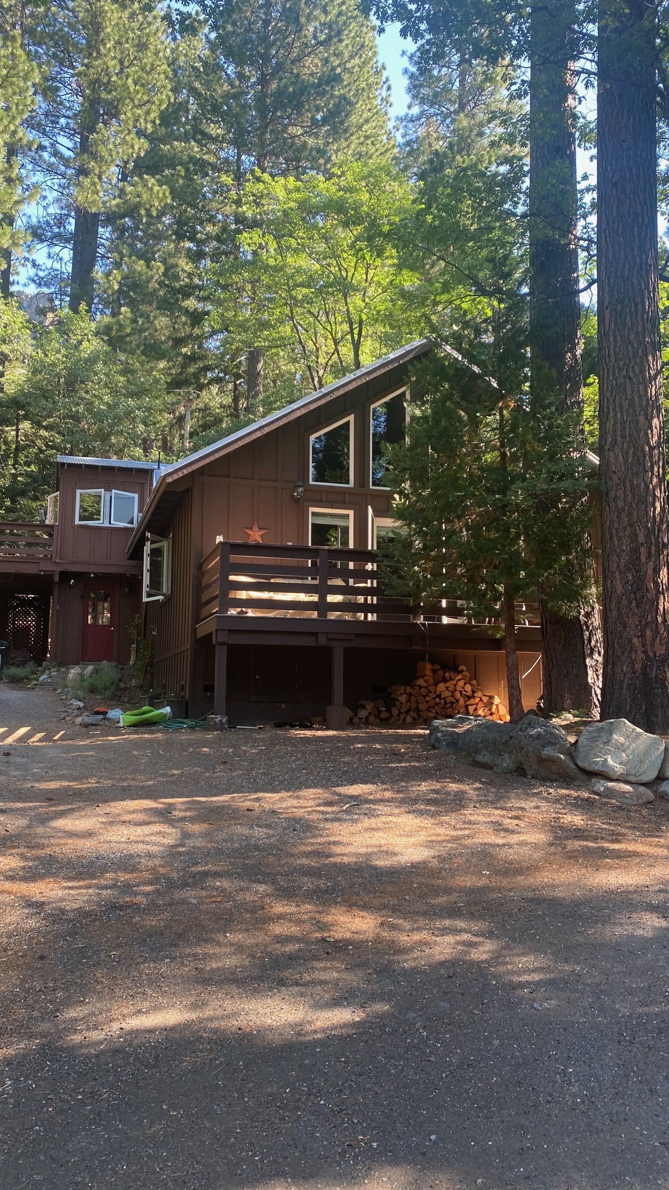 Une cabane dotée d’une terrasse, entourée d’arbres.