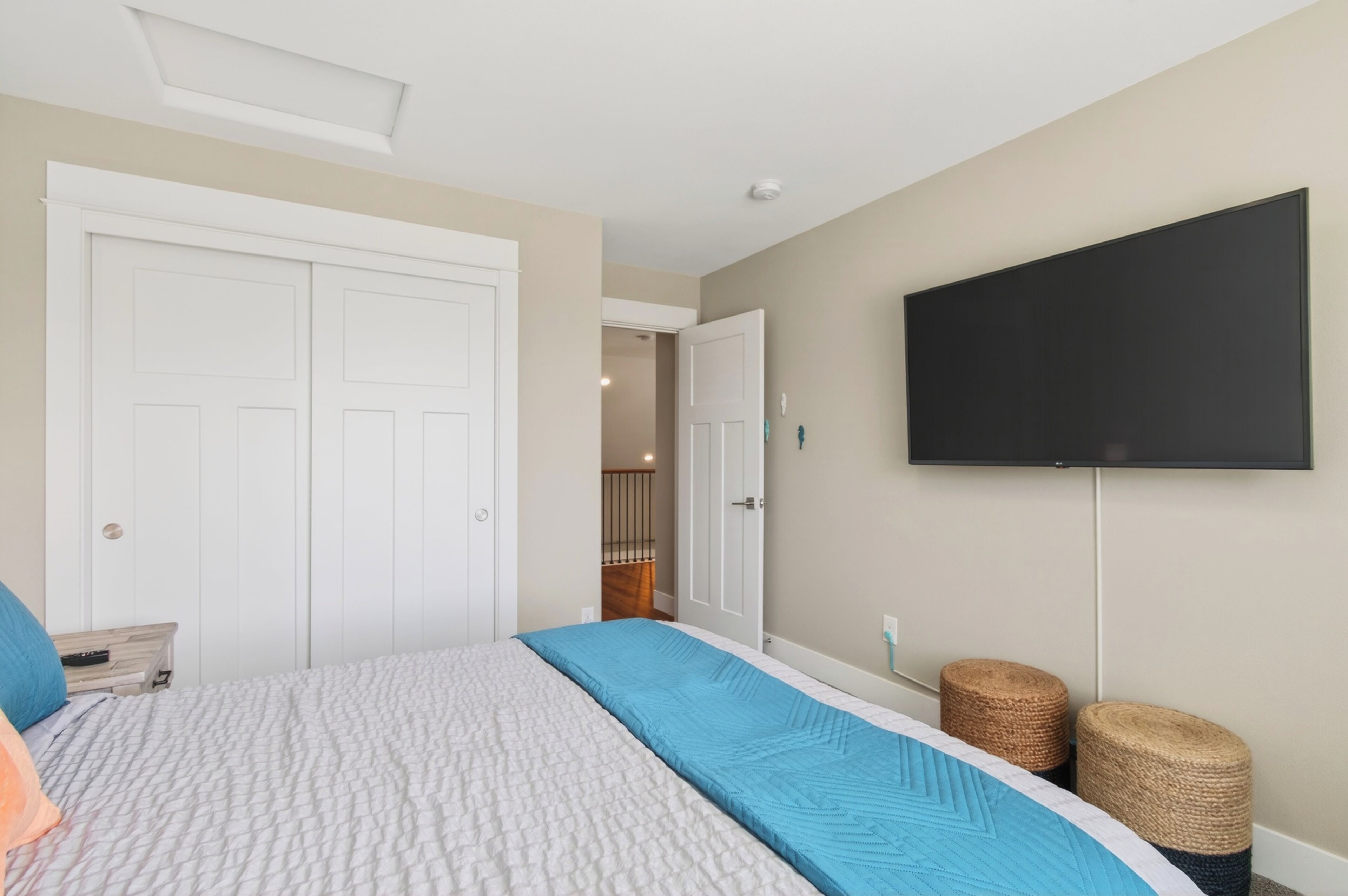 A bedroom with a bed, a TV, a door, and a staircase.