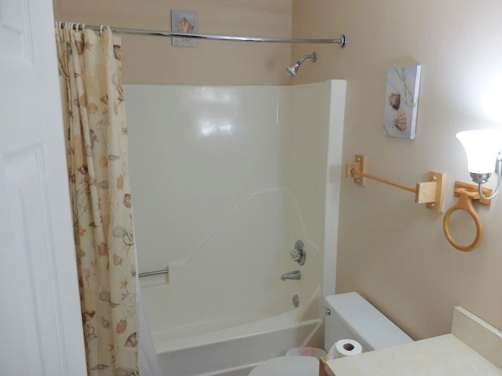 A bathroom with a shower, toilet, and a towel rack.