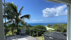 A balcony with a view of the ocean, a covered grill, and a seating area. -  MAGNIFIQUE VILLA KYLA'S  the most beautiful sea view in the Caribbean with POOL (Collectivity of Saint Martin)