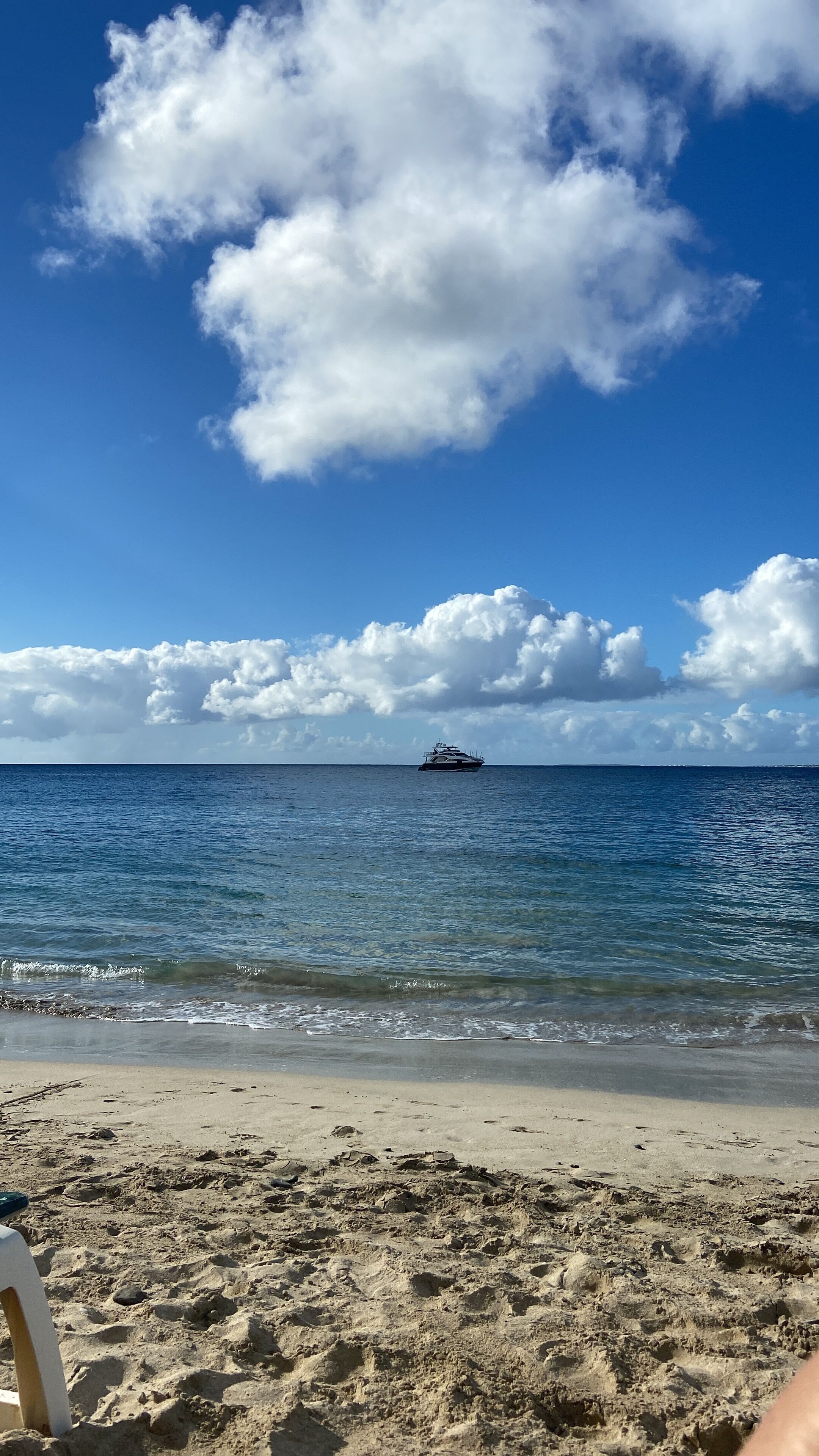 Une plage avec un bateau visible au loin, un ciel dégagé et une rive sablonneuse.