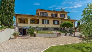 A two-story house with a tiled roof, a gravel driveway, and a well-maintained lawn. - Santa Margherita - NINFEA (Poggibonsi)
