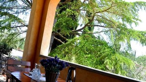 A wooden table with a basket of flowers, a cup, and a plate of pastries, set against a window overlooking a lush green landscape. - Santa Margherita - NINFEA (Poggibonsi)