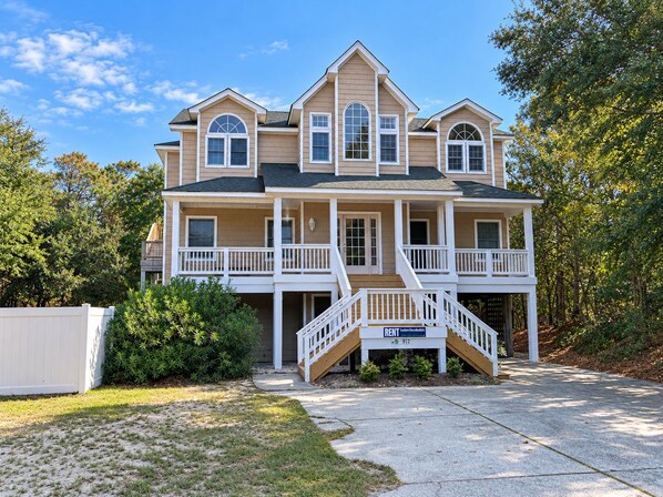 A two-story house with a front porch, multiple windows, and a staircase leading to the entrance.