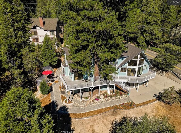 Surrounded by dense trees, this two-story house offers a balcony and covered patio area.
