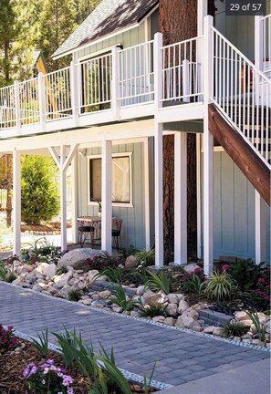 Relax on the serene outdoor deck surrounded by lush greenery and a stone pathway.