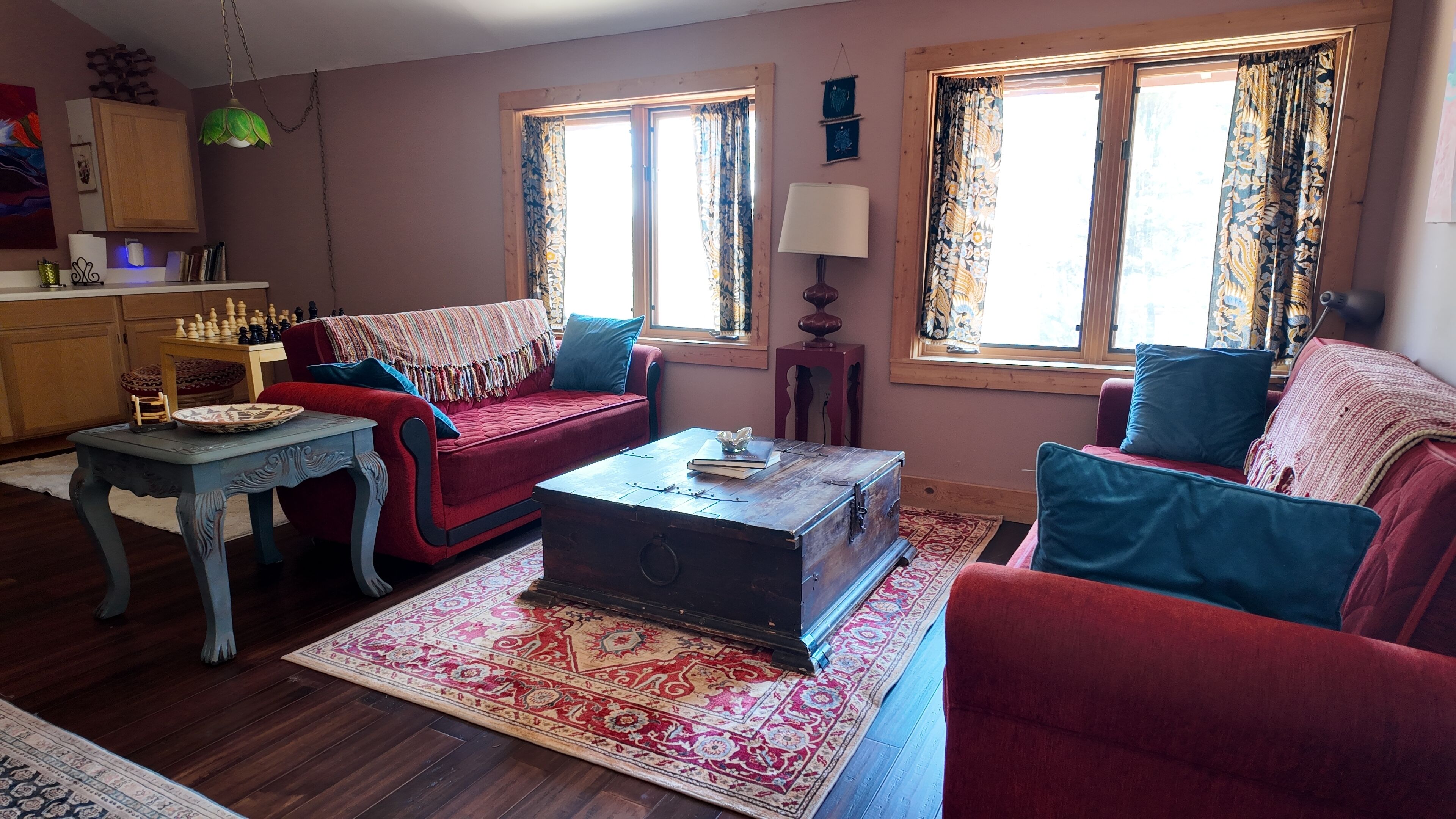 A cozy living room with a red sofa, a wooden coffee table, and a patterned rug.