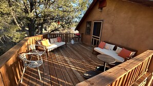 A wooden deck with a sofa and chairs, a grill, and a door leading to the interior. - Artist Retreat~Forest Getaway~Adventurers~Hunters~Writers~Nature Lovers (El Rito)