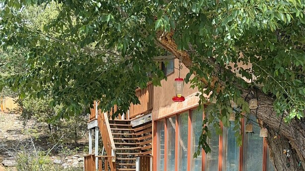 A pathway leading to a building with a wooden staircase, stone walls, and a large window. - Artist Retreat~Forest Getaway~Adventurers~Hunters~Writers~Nature Lovers (El Rito)