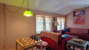 A cozy living room with a chessboard, a red sofa, a patterned throw, and a painting on the wall. - Artist Retreat~Forest Getaway~Adventurers~Hunters~Writers~Nature Lovers (El Rito)