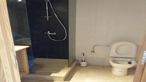 Un baño pequeño con inodoro, ducha y lavamanos.
