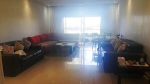 Amplia sala de estar con un gran ventanal, un conjunto de sofás y una mesita de centro.