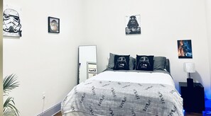Cozy retreat with a neatly arranged bed, bedside table, and Star Wars-themed artwork.