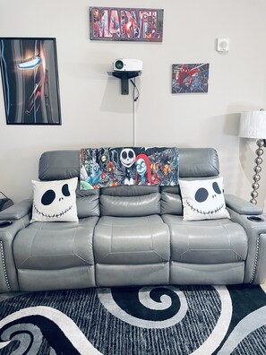 Relax in this stylish living room with a sofa, projector, and unique throw pillows.