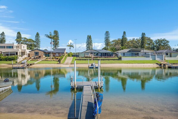 Una propiedad frente al agua con un muelle, un bote pequeño y casas con vistas al mar.