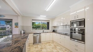Eine moderne Küche mit weißen Schränken, einem Geschirrspüler, einer Mikrowelle und einem Backofen.