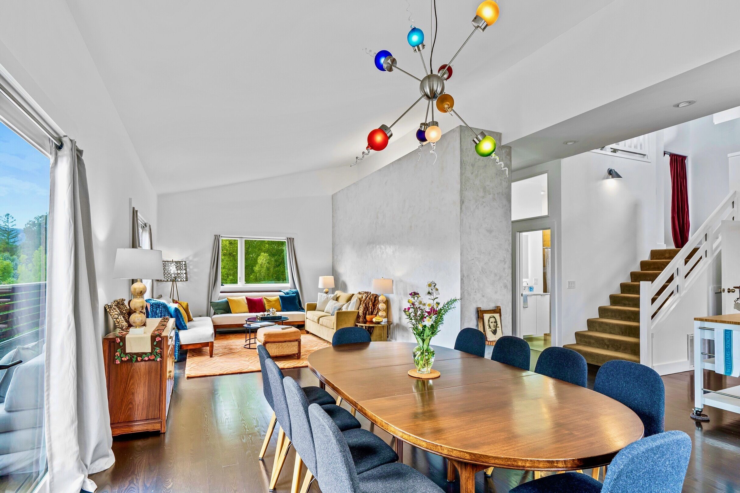 Un salon moderne avec une table à manger en bois, des chaises bleues et un lustre coloré.