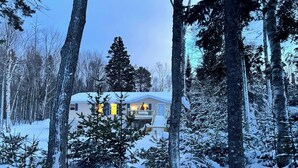Eine Hütte, umgeben von schneebedeckten Bäumen.