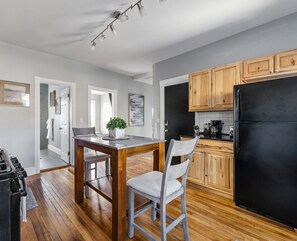 Une cuisine moderne avec des meubles en bois, un réfrigérateur noir et un coin repas comprenant une table en bois et deux chaises.