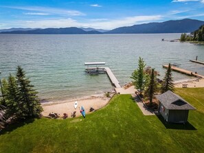 A lakeside property with a dock, a small cabin, and a grassy area with outdoor seating.