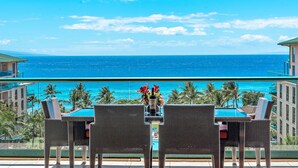 Ein Balkon mit Tisch und Stühlen mit Blick auf einen Pool und den Ozean.