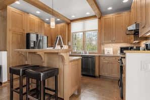 A kitchen with wooden cabinets, a stainless steel refrigerator, a microwave, and a dishwasher.
