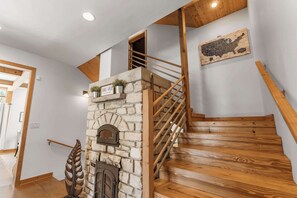A wooden staircase with a stone fireplace, a wooden ceiling, and a welcome sign.