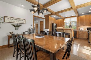 A spacious dining area with a large wooden table and chairs, a kitchen with wooden cabinets, and a sign on the wall. - Private Home in Sister Bay-Door County, 5 BR (Sister Bay)