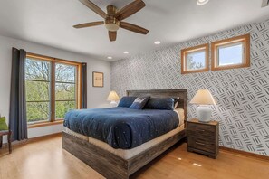 A bedroom with a bed, two bedside tables, a ceiling fan, and a window with a view. - Private Home in Sister Bay-Door County, 5 BR (Sister Bay)