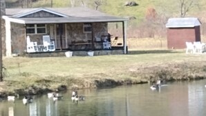 A lakeside cabin with a covered porch and outdoor seating.